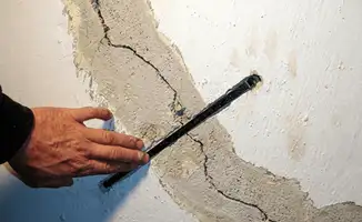 A wall with a large crack is being inspected by a professional in Rochester, NY